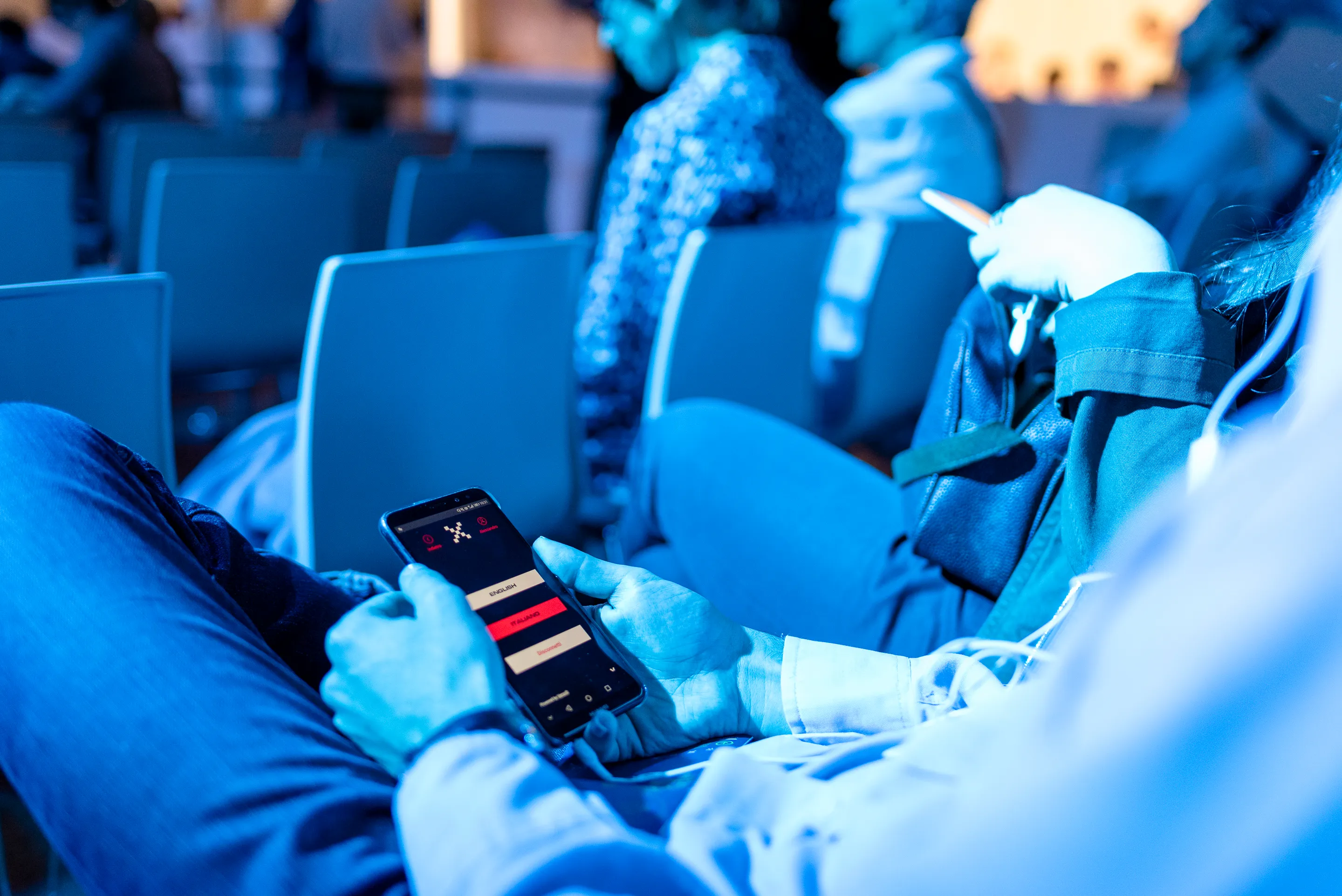 Participant pendant une conférence utilisant l'application sur smartphone pour écouter la traduction